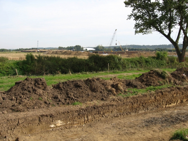 Op de achtergrond het verwerkingsbekken met de ingepakte brug van Bunde. Op de voorgrond proefsleuven ten behoeve van nieuw archeologisch onderzoek bij Hartelstein. Op de achtergrond het verwerkingsbekken met de ingepakte brug van Bunde. Op de voorgrond proefsleuven ten behoeve van nieuw archeologisch onderzoek bij Hartelstein.