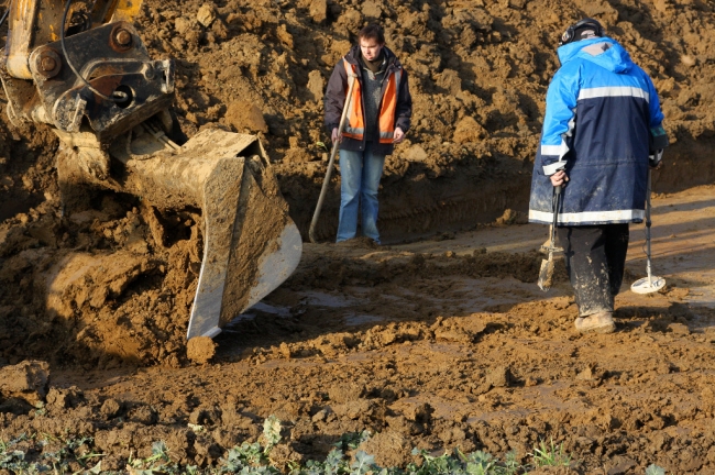 Een graafmachine schraapt de bovenste laag weg. Eventuele sporen in die bovenste laag zijn al lang verdwenen omdat elk jaar de grond werd omgeploegd. Een graafmachine schraapt de bovenste laag weg. Eventuele sporen in die bovenste laag zijn al lang verdwenen omdat elk jaar de grond werd omgeploegd.
