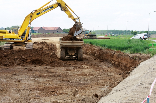 Voor de aanleg van de ongelijkvloerse kruising wordt een stevig fundament gemaakt. De dekgrond wordt daarom weggegraven tot op de onderliggende kiezellaag. De dekgrond wordt opgeslagen in het gronddepot te Borgharen. Voor de aanleg van de ongelijkvloerse kruising wordt een stevig fundament gemaakt. De dekgrond wordt daarom weggegraven tot op de onderliggende kiezellaag. De dekgrond wordt opgeslagen in het gronddepot te Borgharen.