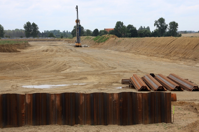 Op de voorgrond de damwand die de buitenste ring vormt van de haven.
Deze buitenste damwand wordt op 4 mtr afstand van de betonietwand geplaatst. Op de voorgrond de damwand die de buitenste ring vormt van de haven.
Deze buitenste damwand wordt op 4 mtr afstand van de betonietwand geplaatst.