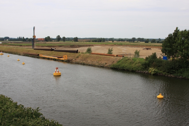 Zicht vanaf de brug van Bunde. Op de kanaaldijk ligt het materiaal al klaar om in het Julianakanaal een damwand te slaan. Zicht vanaf de brug van Bunde. Op de kanaaldijk ligt het materiaal al klaar om in het Julianakanaal een damwand te slaan.