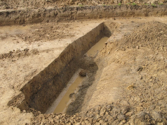 Sleuf met grondverkleuring, voor een archeoloog een gegeven dat nadere bestudering vereist.