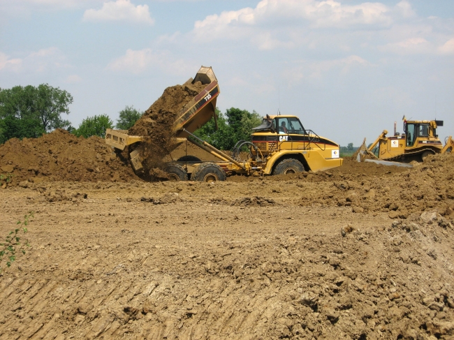 Hier lost een knikgestuurde dumptruck zijn lading. Afhankelijk van het type dumper kan tussen de 25 en 40 ton geladen worden. Hier is een CAT 735 aan het werk met een laadvermogen van 32,7 ton. Hier lost een knikgestuurde dumptruck zijn lading. Afhankelijk van het type dumper kan tussen de 25 en 40 ton geladen worden. Hier is een CAT 735 aan het werk met een laadvermogen van 32,7 ton.