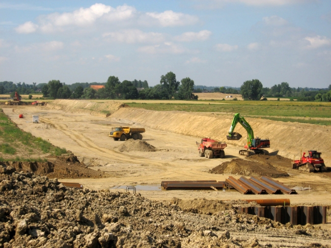 Overzichtsfoto van het westelijk deel van het verwerkingsbekken. Het is niet voor te stellen dat men pas 2 maanden aan de bezig is. Er is inmiddels een ongelofelijke hoeveelheid grond verplaatst. Ongeveer iedere twee minuten wordt er ca 35 ton grond weggebracht naar de gronddepots. Overzichtsfoto van het westelijk deel van het verwerkingsbekken. Het is niet voor te stellen dat men pas 2 maanden aan de bezig is. Er is inmiddels een ongelofelijke hoeveelheid grond verplaatst. Ongeveer iedere twee minuten wordt er ca 35 ton grond weggebracht naar de gronddepots.