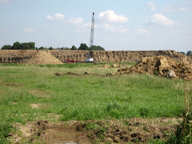 Op de achtergrond het gronddepot bij Voulwammes met de installatie die de damwanden aan het slaan is.