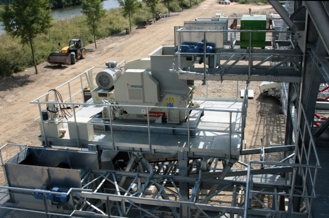 De steenbreker van bovenaf gezien. Het betreft hier een compacte mobiele breekinstallatie van Metso, type Nordberg C96. Hij kan stenen breken tot een formaat van maximaal 26 cm doorsnee.