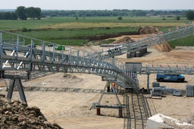 Aan de westzijde van de grint-terp wordt een identieke transportinstallatie gebouwd om een voorselectie te maken op het aangevoerde grint. Aan de westzijde van de grint-terp wordt een identieke transportinstallatie gebouwd om een voorselectie te maken op het aangevoerde grint.