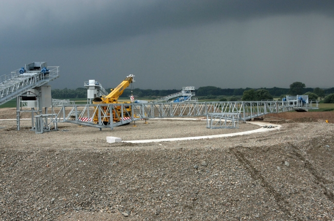 Bovenop de terpen wordt aan de transportband een zwenkarm gemonteerd, die over de betoncirkel van links naar rechts gaat draaien en zo het grind verdeelt over de 2 tunnels. Het grind bovenop de tunnels komt zo'n 5m hoger te liggen dan de terpen. Bovenop de terpen wordt aan de transportband een zwenkarm gemonteerd, die over de betoncirkel van links naar rechts gaat draaien en zo het grind verdeelt over de 2 tunnels. Het grind bovenop de tunnels komt zo'n 5m hoger te liggen dan de terpen.