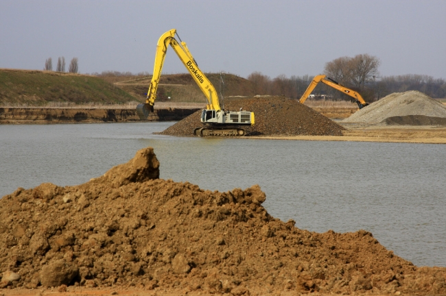 Op de achtergrond de dekgrondberging met het uitkijkpunt. De graafmachines kunnen nog wel effe vooruit. Dag in dag uit wordt de kiezel uit de diepte naar bovengehaald. Op de achtergrond de dekgrondberging met het uitkijkpunt. De graafmachines kunnen nog wel effe vooruit. Dag in dag uit wordt de kiezel uit de diepte naar bovengehaald.