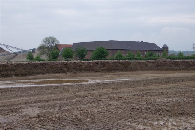 Noordelijke begrenzing van de dekgrondberging ter hoogte van hoeve Hartelstein. Op de achtergrond de verwerkingsinstallatie en het grinddepot. Noordelijke begrenzing van de dekgrondberging ter hoogte van hoeve Hartelstein. Op de achtergrond de verwerkingsinstallatie en het grinddepot.