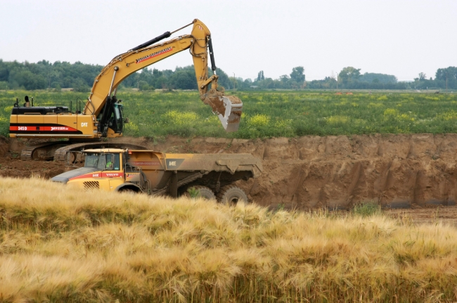 Op de voorgrond staat het laatste graan nog te rijpen. Na de oogst zal ook dit stuk worden afgegraven. 