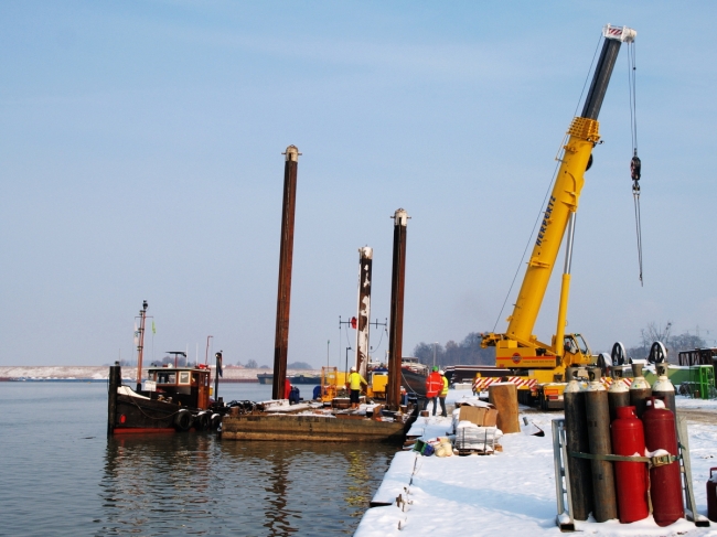 Een ponton-met-poten, zgn. spudpoten waarmee de ponton op de onderwaterbodem kan staan, wordt gereed gemaakt. Dit ponton is nodig bij het weer op de gewenste diepte brengen van de werkhaven. Een ponton-met-poten, zgn. spudpoten waarmee de ponton op de onderwaterbodem kan staan, wordt gereed gemaakt. Dit ponton is nodig bij het weer op de gewenste diepte brengen van de werkhaven.