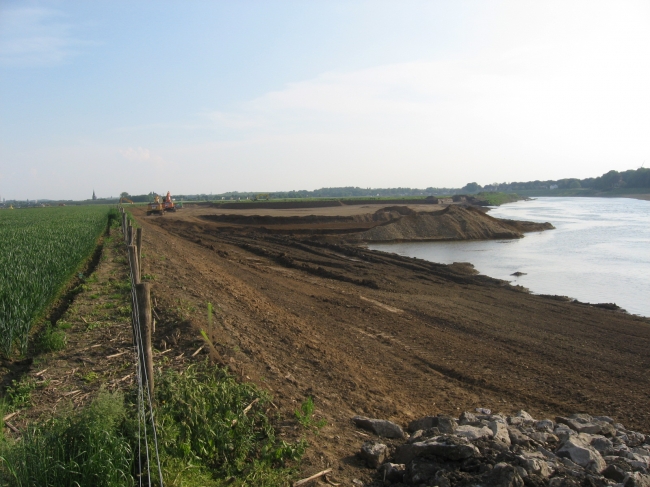 De stroomgeulverbreding ten zuiden van Itteren. Aangezien hier niet zoals in de dekgrondberging diep gegraven hoeft te worden, vordert het werk hier razendsnel. De stroomgeulverbreding ten zuiden van Itteren. Aangezien hier niet zoals in de dekgrondberging diep gegraven hoeft te worden, vordert het werk hier razendsnel.