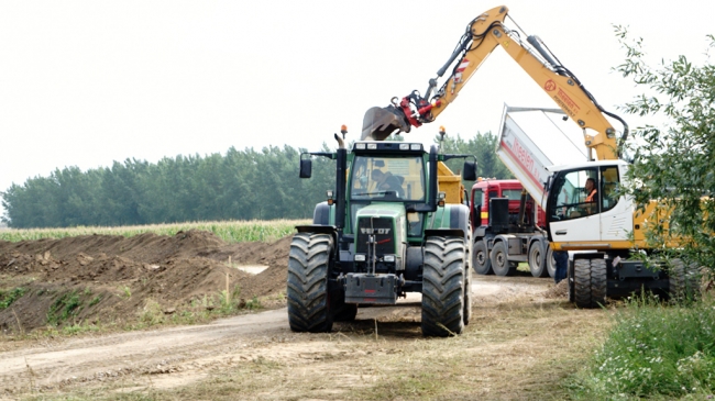 Allerlei materieel wordt ingezet om het wandelpad rondom de recreatievijver op tijd klaar te krijgen. Het wandelpad maakt aan de zuid-oost zijde over een lengte van ongeveer 200m een uitstapje naar een lager nivo. Ik weet niet of dit voor mensen met een scootmobiel een probleem wordt. Prettiger zou het zijn als het pad op maaiveld nivo ook nog rechtdoor zou lopen zodat je de keus hebt.  