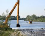 Met dumpers wordt het nodige materiaal voor de aanleg van de drempels naar de plaats van bestemming gereden. In de maas is een soort rijweg uitgezet, gemarkeerd met grote stenen. (26-9-2008 - Jan Dolmans)