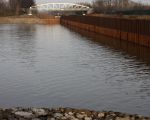 De inlaat vanuit het Julianakanaal naar de \'binnenhaven\'. De waterhoogte van het Julianakanaal staat gelijk aan de bovenkant van de lichte verkleuring van de damwand. De bodem van de invaart ligt 4m onder het waterpeil van het Julianakanaal. De diepgang van de schepen over het Julianakanaal mag maximaal 3,5m bedragen in verband met de op 3,5m gelegen betonnen drempels in de sluiscomplexen. (8-12-2008 - Jan Dolmans)
