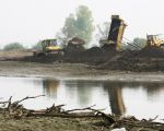 Met de afgegraven grond van de Maasoever wordt de achterliggende plas gedeeltelijk opgevuld. (22-4-2009 - Jan Dolmans)