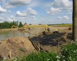 Twee machines halen het grind uit de grond en leggen een klein depot aan. De derde machine belaadt vervolgens de knikdumpers die het toutvenant naar het grote depot bij de verwerkingshaven brengen waar het verder gescheiden wordt in verschillende fracties. Vervolgens wordt het eindproduct via het Julianakanaal verder getransporteerd met schepen. (4-5-2009 - Han Hamakers)