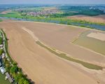 Ter voorkoming van geluidsoverlast is de dekgrond gebruikt om een geluidsscherm te bouwen. Links woonboten in het afvoerkanaal. Aan de bovenkant loopt de Maas met daarachter Borgharen. (30-4-2009 - Bron: ing. Hans Brinkhof)