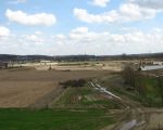 Links ligt Hoeve Hartelstein. Duidelijk is te zien hoeveel dekgrond al is weggehaald. Aan de hand van de paaltjes kan men zien waar nog dekgrond weggehaald moet worden. Aan de hand van de huidige planning wordt de dekgrondberging nog dit jaar klaar gemaakt. Begin 2011 kan dan begonnen worden met het verleggen van de Geul. (2-4-2010 - Han Hamakers)