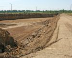 Links bij de lantaarnpalen loopt nog de oude weg naar Herbricht. Inmiddels is men al vergevorderd met de aanleg van de nieuwe weg meer landinwaarts, rechts op de foto. Het gedeelte links van de nieuwe weg zal ook worden afgegraven in het kader van de oeververbreding van de Maas.  (16-6-2010 - Jan Dolmans)