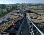 Bovenop de installatie staande, kijkend naar het zuiden, zie je links het Julianakanaal en aan de voet van de installatie zie je een dumper toutvenant lossen. Verder naar achter de dekgrondberging in het Hartelsteinerveld die alweer gedeeltelijk opgevuld is.  (11-10-2010 - Reen van Beek)