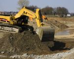 Een Caterpillar 385 CL is in Borgharen ingezet om dumpers te beladen.
Ik heb even geklokt en binnen 1 minuut was een dumper door deze gigant beladen met 45 ton kiezel, in slechts 3 keer scheppen. De bak van deze graafmachine kan per keer 9m3 (15 ton) kiezel opscheppen. De machine is zelf dan ook aan de maat met zo'n 100ton eigengewicht en zijn motor van 530 pk. Dir schiet wel op.  (28-3-2011 - Jan Dolmans)