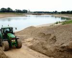 Inmiddels is men al wekenlang aan het pompen om het waterpeil van de vijver enkele meters omlaag te krijgen. De vijver staat echter via de grindlagen in verbinding met de Maas waardoor de vijver ondergronds steeds weer gevuld wordt. De verlaging is nodig om de opgeslagen dekgrond te verspreiden. Jammer dat er geen eiland in de vijver is overgebleven.    (20-7-2016 - Jan Dolmans)